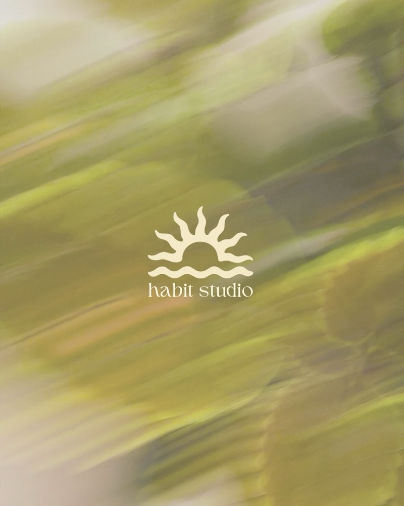 Habit studio-logo met een zon boven golven, crème op een bewogen groene achtergrond